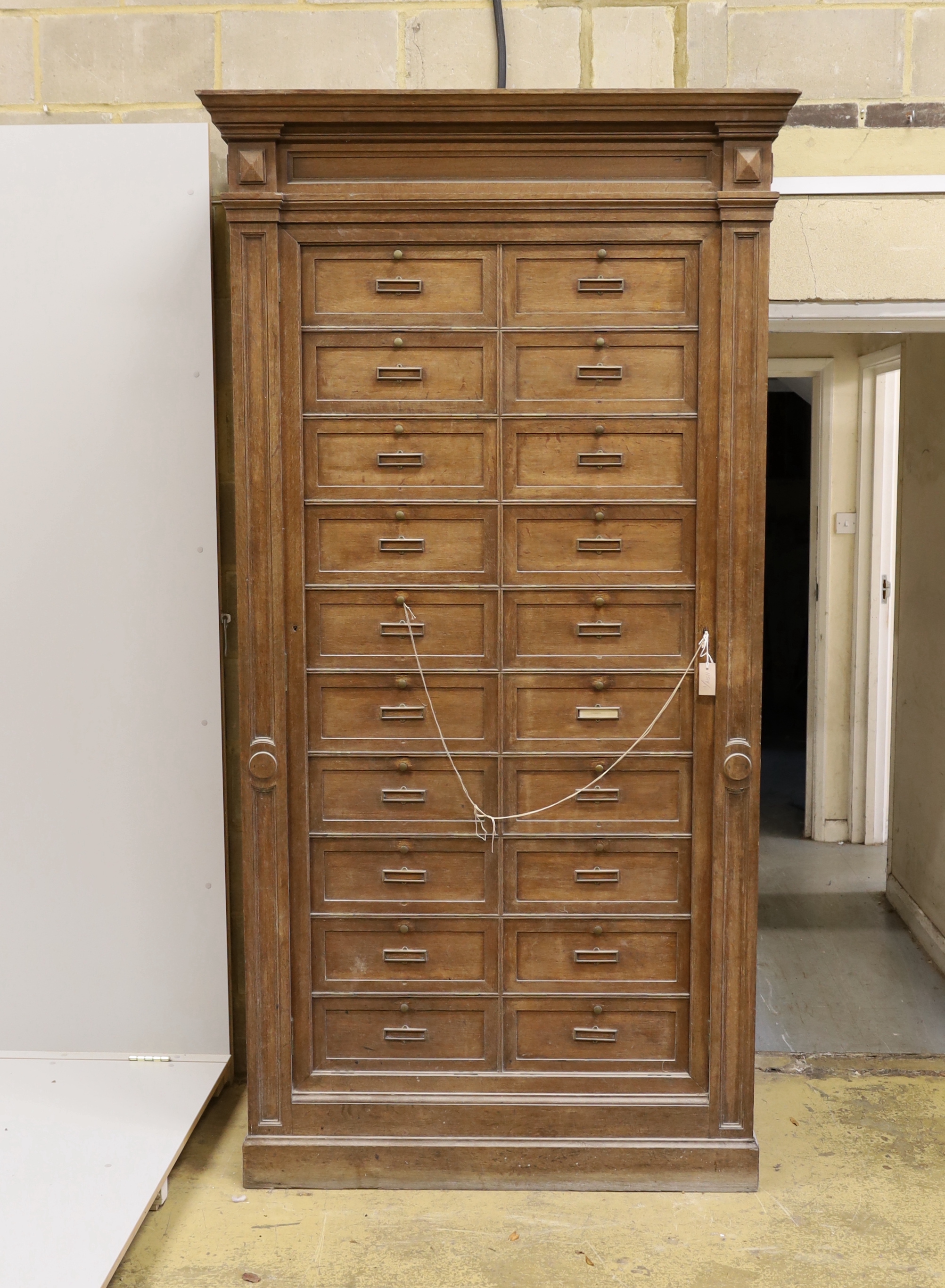 An early 20th century French oak notaries cabinet with twenty fall front compartments, width 125cm, depth 60cm, height 240cm